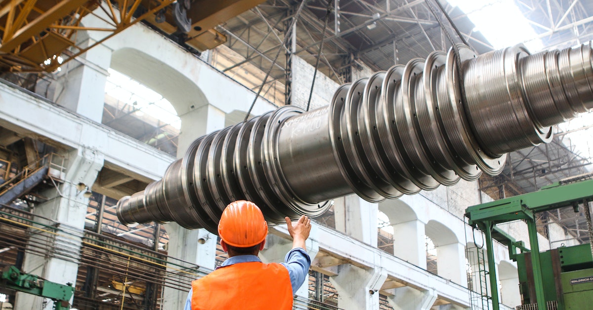 man standing beside heavy equipment on a plant